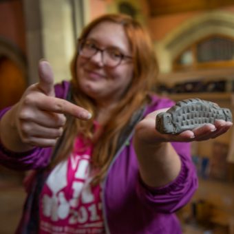 A woman holding up a clay object