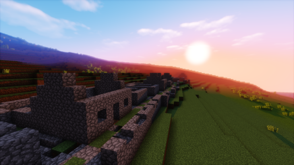 Photo of a site in Minecraft featuring a stone square built house with an orange sunset in the background.