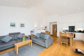 Photo of a large, open-plan living and dining area, with double height ceiling, two sofas and dining table.