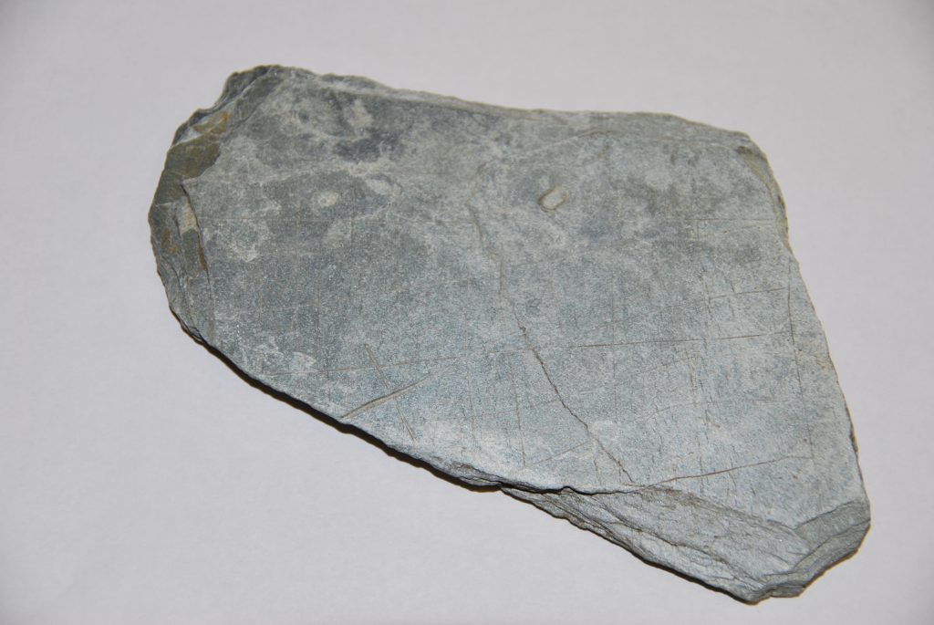 Photo of a triangular piece of slate with musical notations carved on in notches.