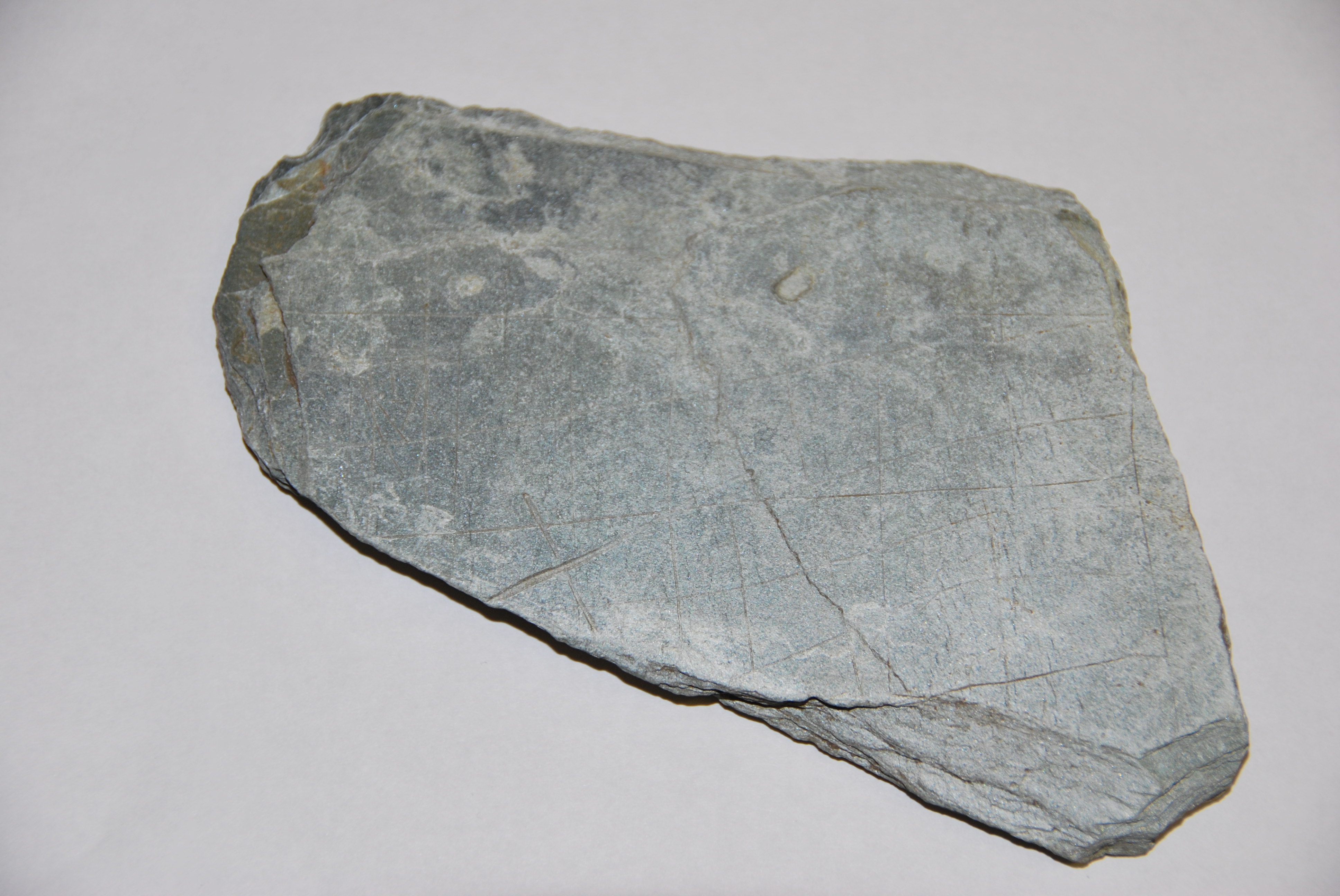 Photo of a triangular piece of slate with musical notations carved on in notches.