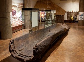 Photo of a large wooden logboat inside a museum gallery
