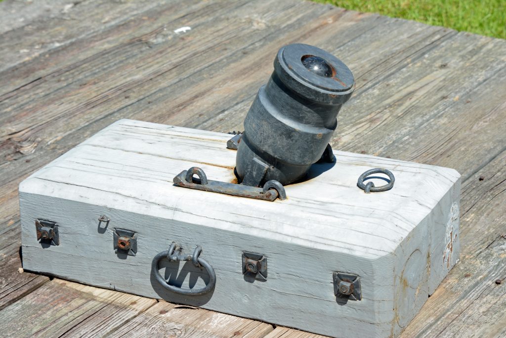 Photo of a replica mortar, a small rectangular wooden base with a small metal canon protruding from the top. 
