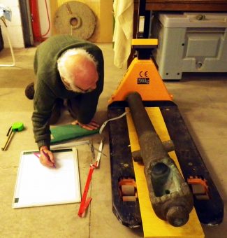 A person crouching down to look at an old, large object