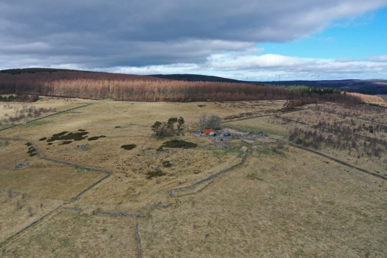 Aerial photo of an area of farmland with decaying buildings on it.