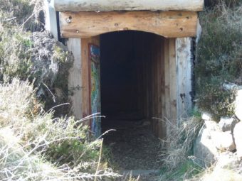 Photo of a square opening in the side of a bank leading to a roofed chamber.