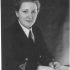 Black and white portrait of a young woman in military uniform sat at a desk.