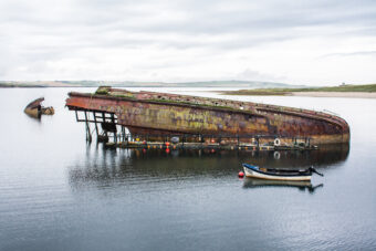 The upturned wreck of a small fishing boat in an island bay