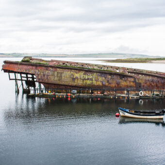 The upturned wreck of a small fishing boat in an island bay