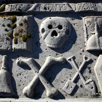 Grave slab with book, skull, hourglass, bell, bones, tools and a coffin