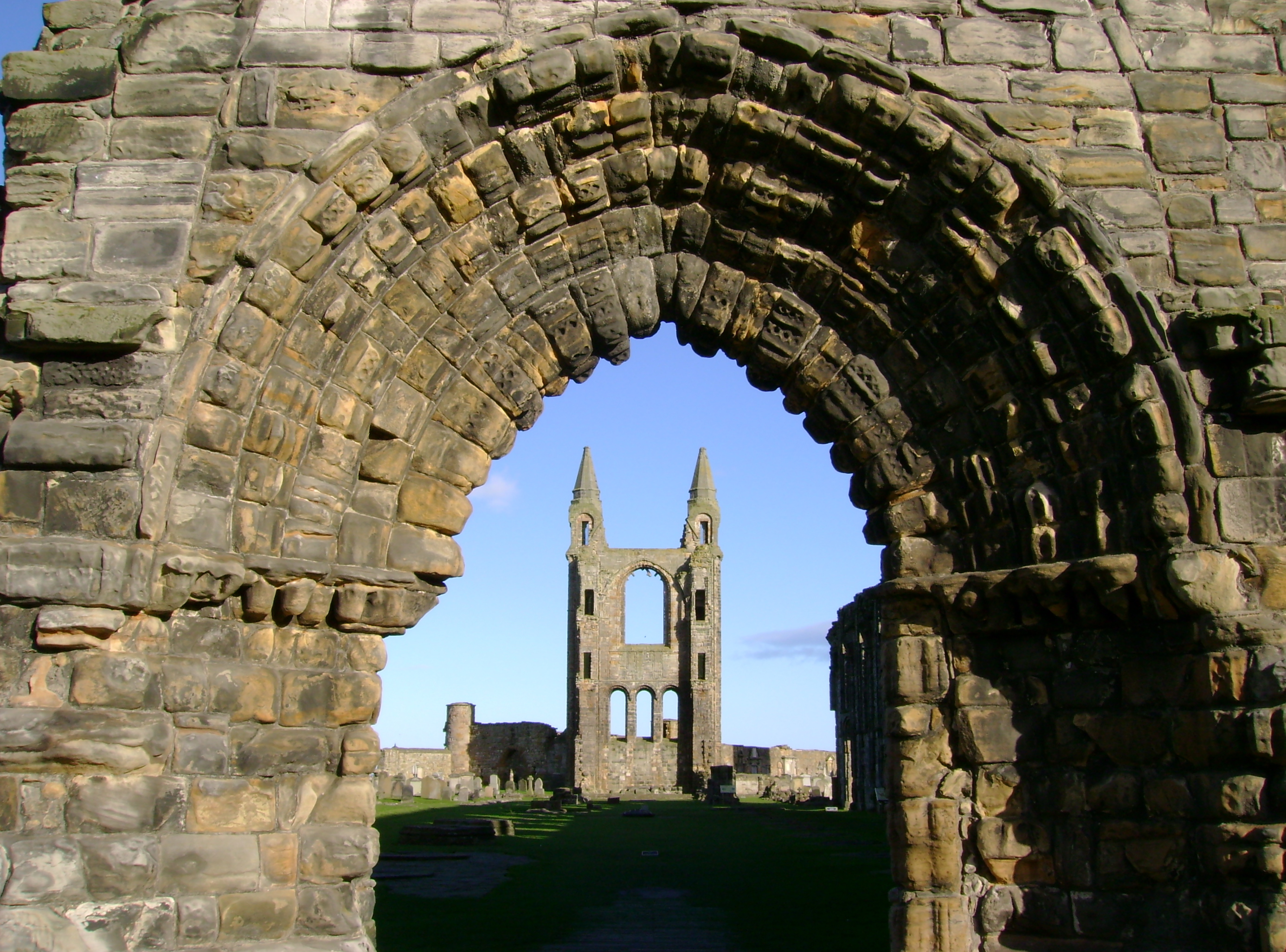 Photo of a ruined cathedral spire through a carved stone archway.