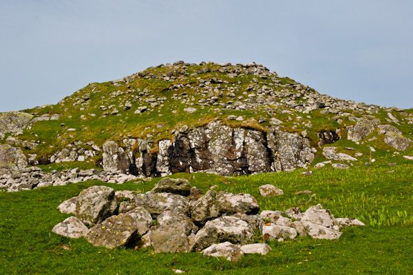 Photo of a gren hill scattered with stones, once a prehistoric dwelling.