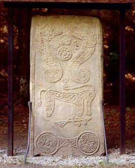 Photo of a square standing stone depicting strange symbols and beasts