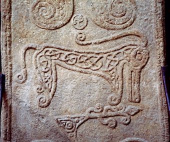Photo of a square standing stone depicting strange symbols and beasts
