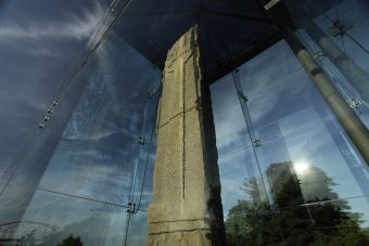 Photo of a tall carved standing stone in a glass case.
