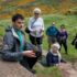 People outdoors listening to a guide on a rock