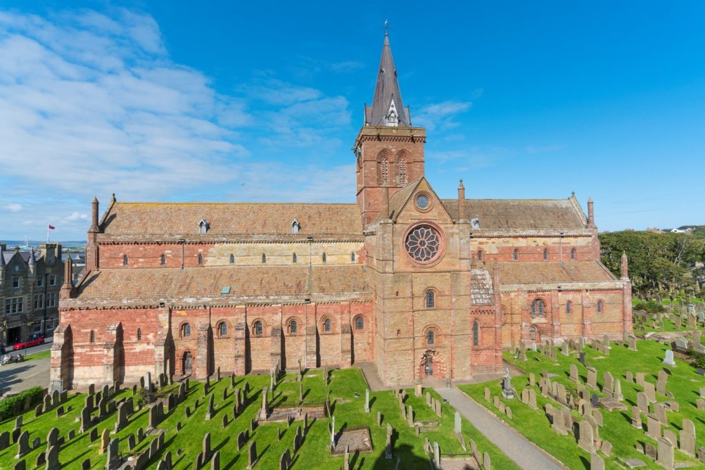 Photo of a red brick cathedral in a graveyard.