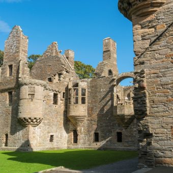 Photo of a ruined, two-storey stone palace, with turrets and curved windows