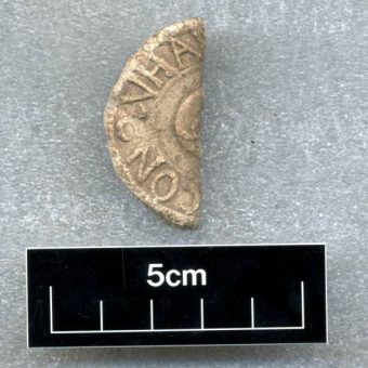 Photo of half of a sandy-coloured lead coin.