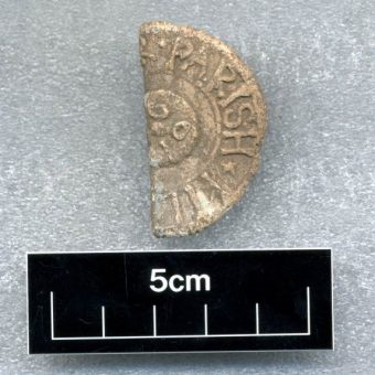 Photo of half of a sandy-coloured lead coin.