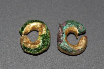 Photo of two gold rings, worn and spattered green decay.