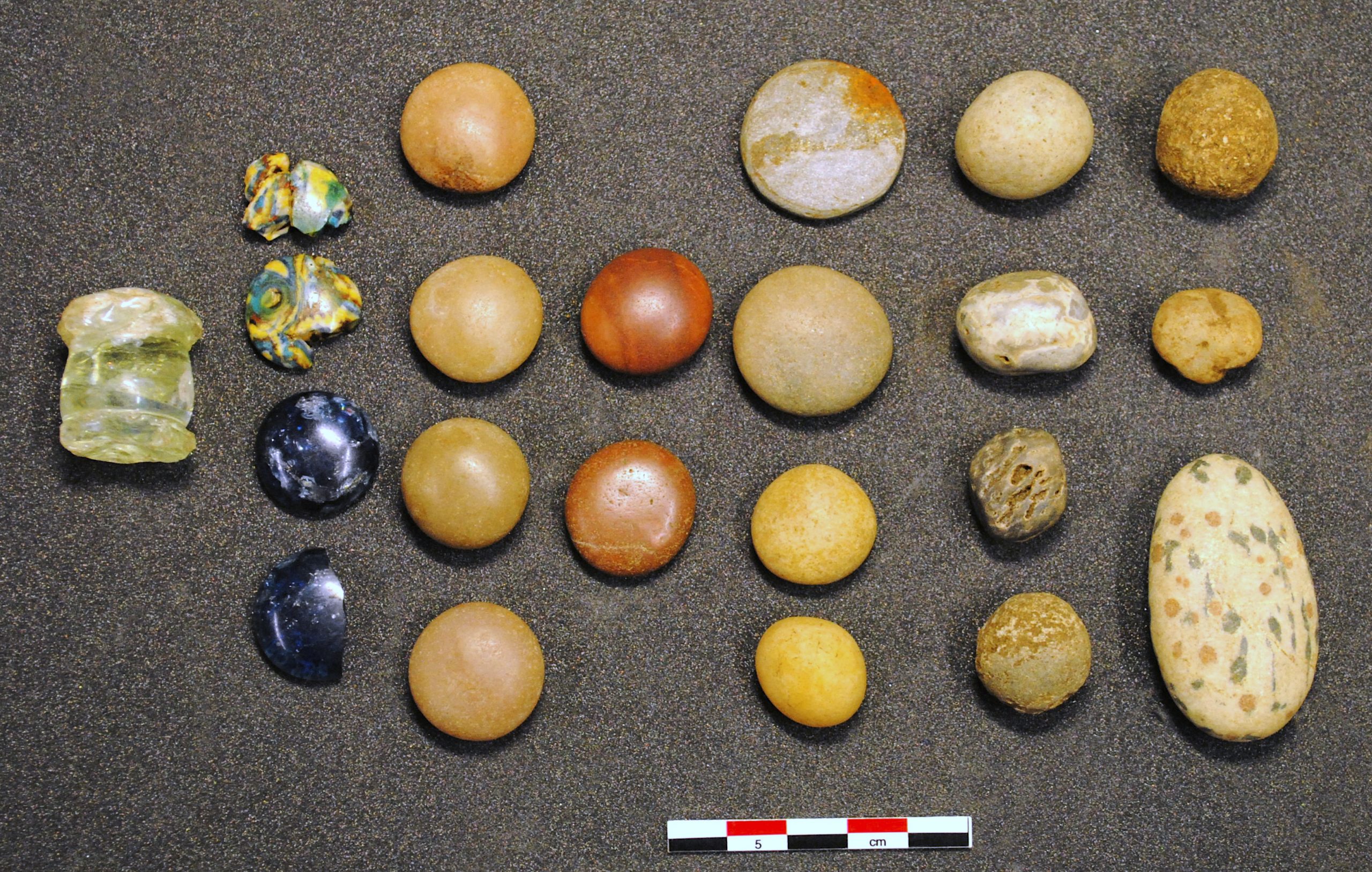 Photo of seven columns of glass beads laid out on a table, of different sizes and colours.