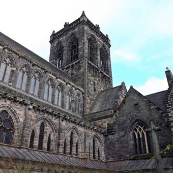 Photo of the corner of a large abbey looking up at the central tower.