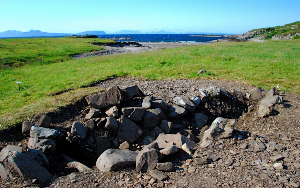 Photo of a burial site on an island with stones lining the long grave.
