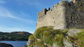 Photo of a square stone castle built on a rock in the sea.