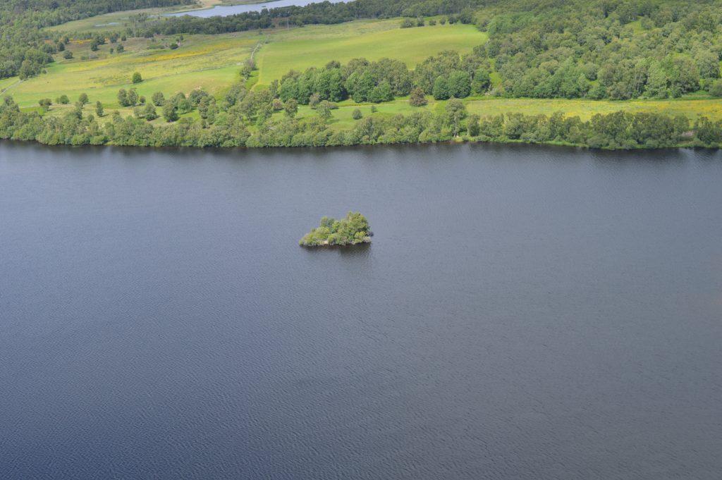 Photo of a loch with a small green islet in the centre.
