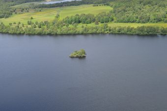 Photo of a loch with a small green islet in the centre.