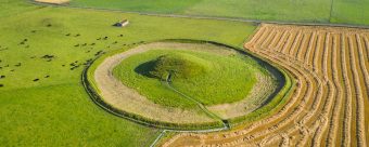 Aerial photo of a circular chambered dwelling in a field.