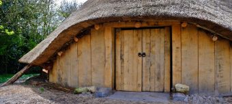 Photo of a replica prehistoric roundhouse with thatched conical roof.