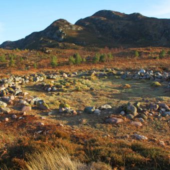 Photo of a large stone circle beneath a hill.