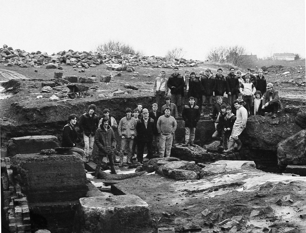 [IMAGE 4: Excavators illustrating the depth of debris that had covered the remains of the ironworks, around 1986.]