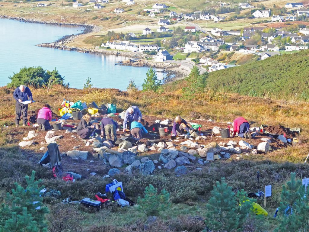 Photo of lots of people digging in an archaeological trench by the sea.