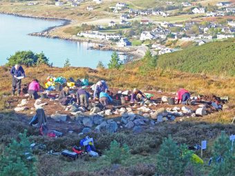 Photo of lots of people digging in an archaeological trench by the sea.