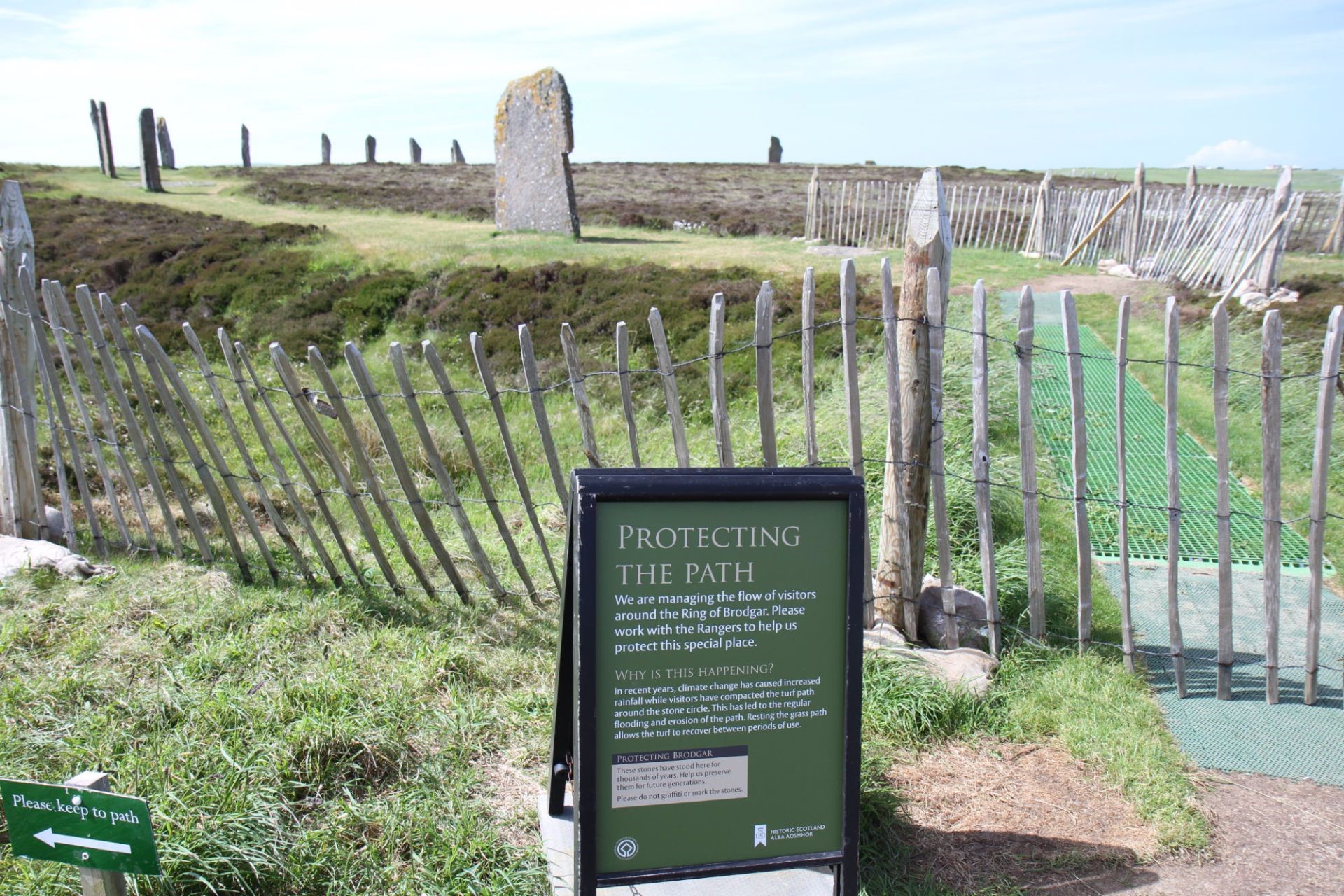 A picture containing fence, grass, and a sign explaining why the path is closed.