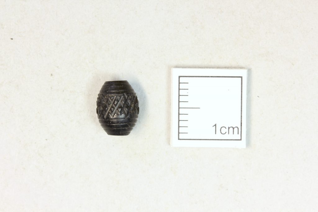 A small decorated bead next to a 1cm marker