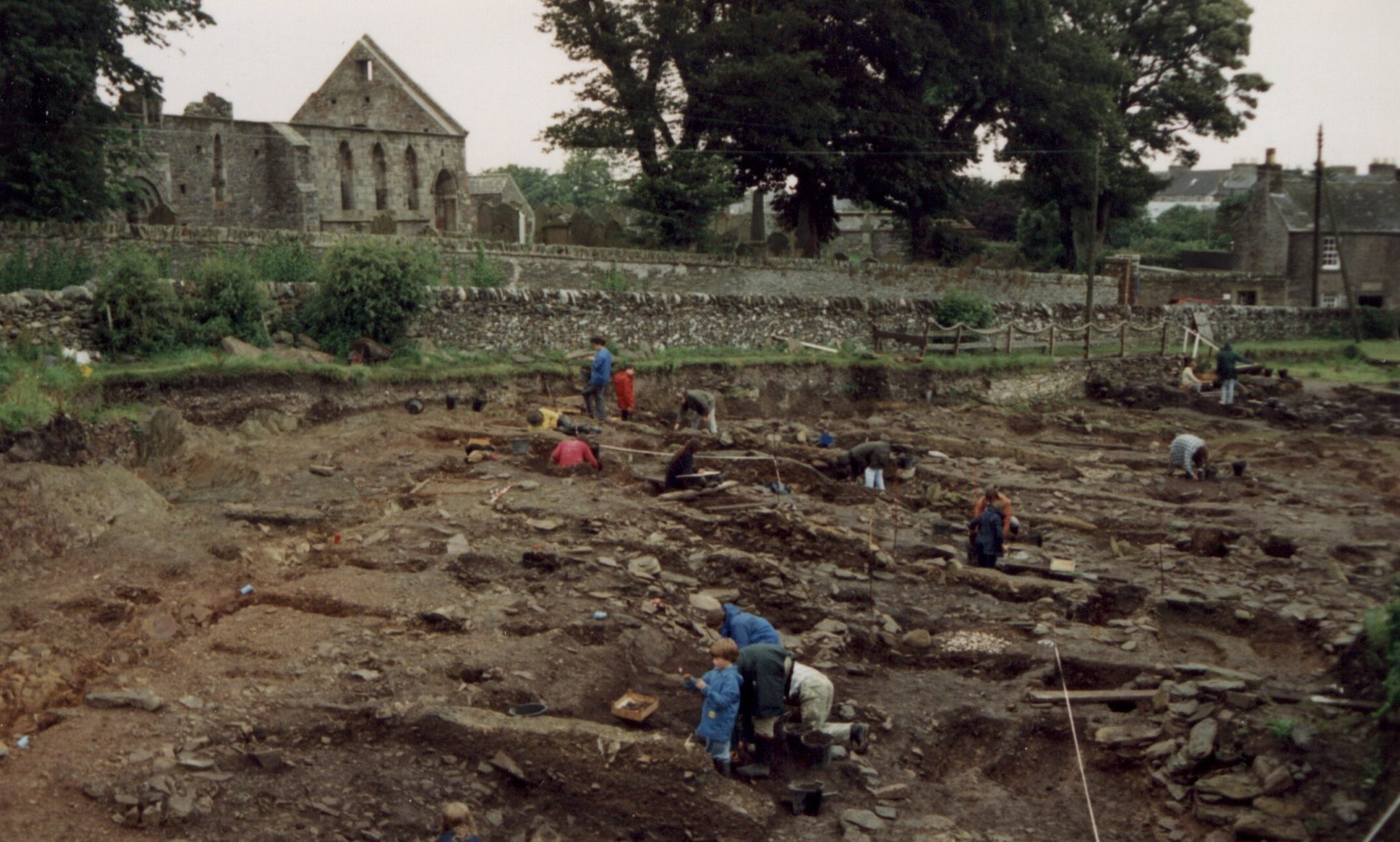 Photo of a burial site by a ruined church being excavated by archaeologists.