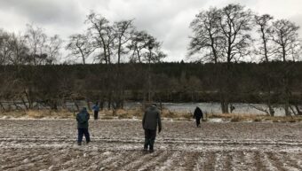 People walking on a frosted field looking at the ground