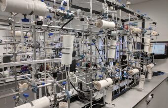 Photo of a science lab with metal frames on tables holding test tubes containing samples
