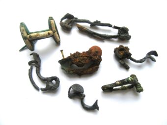 A collection of corroded, prehistoric brooches on a white background.