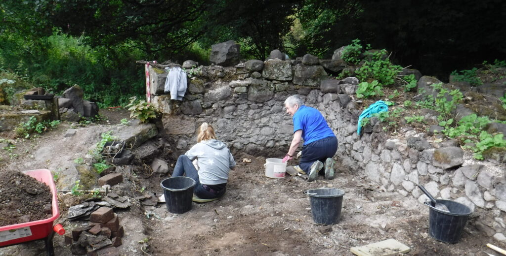 Two people crouching at a dig site