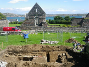 Photo of an archaeological dig in a field behind the ruins of a chapel