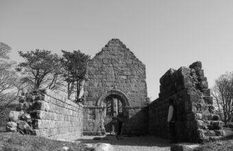 Black and white photo of the remains of a stone chapel
