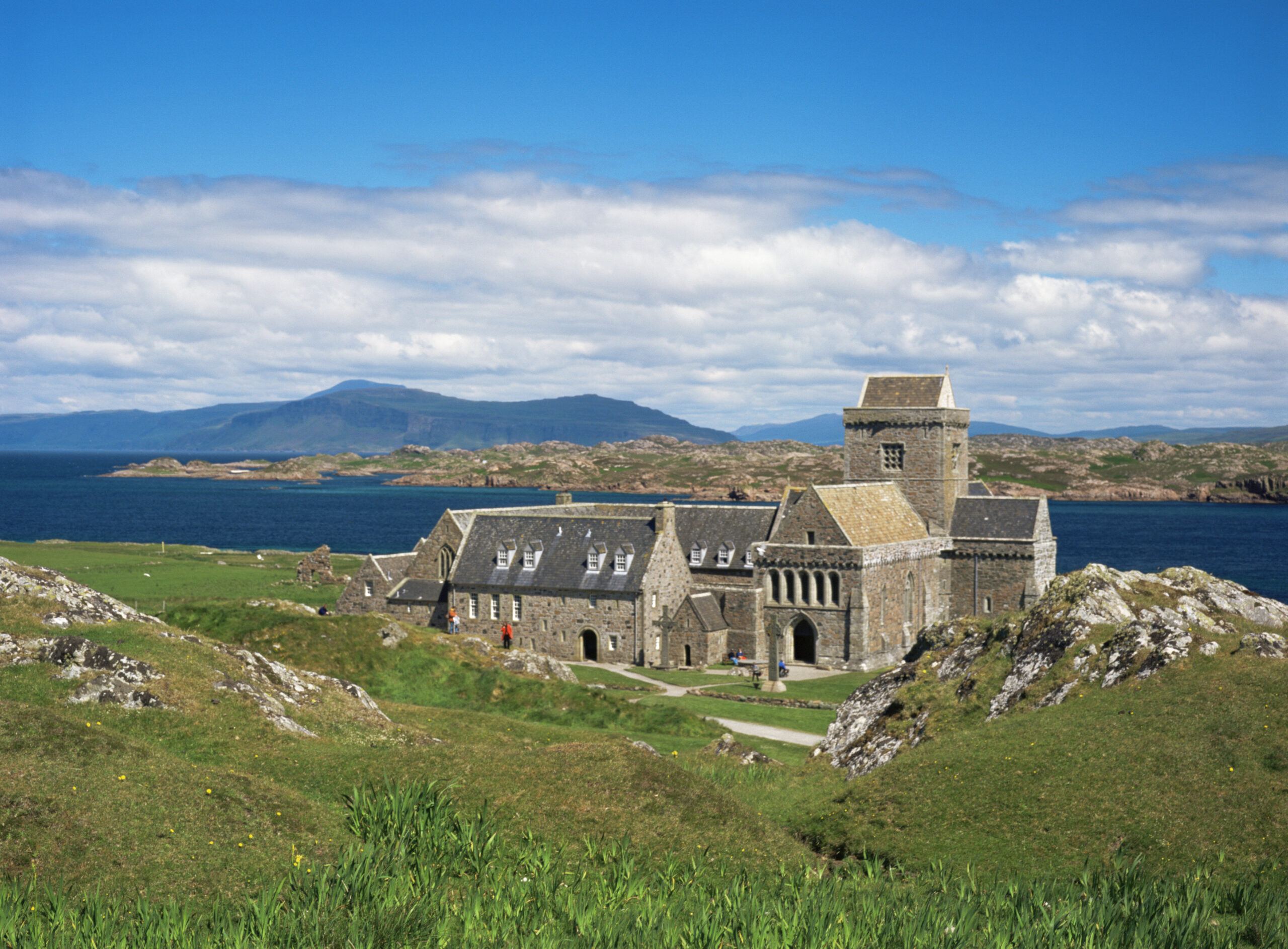 Photo of a medieval stone abbey on an island with the sea in the background.