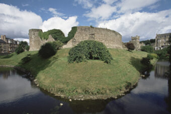 Photo of the curved walls of a stone castle surrounded by water