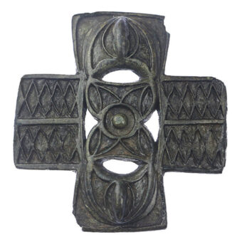 A grey, decorated object in the shape of a cross