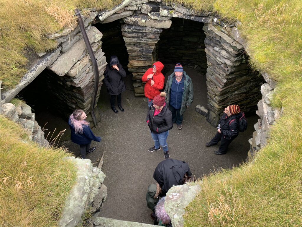 Photo of eight people in waterproof clothing standing in an ancient subterranean dwelling